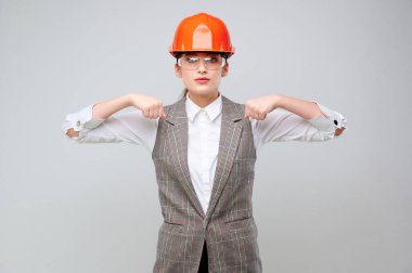 Young woman engineer with protective orange paint and goggles holds do not lead my advertisement in front of you