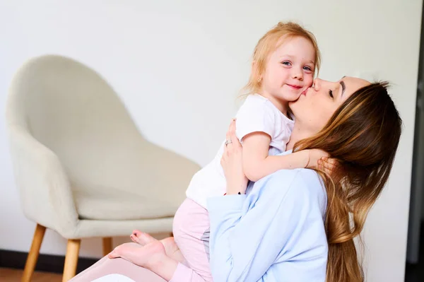 Niña linda abrazos con su mamá en casa. Buena relación con los padres. Madre soltera — Foto de Stock