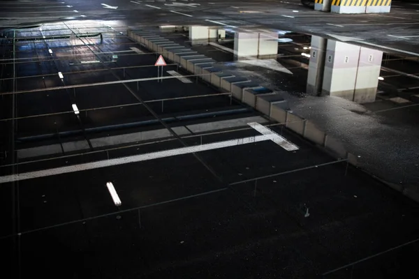 建物の下の駐車場 地下駐車場 駐車場の壁面や天井を反映したアスファルト表面の水溜り — ストック写真