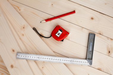 A measuring tape, a square and a pencil. Tools for measuring. Joiner's (carpenter's) workshop. Close-up.