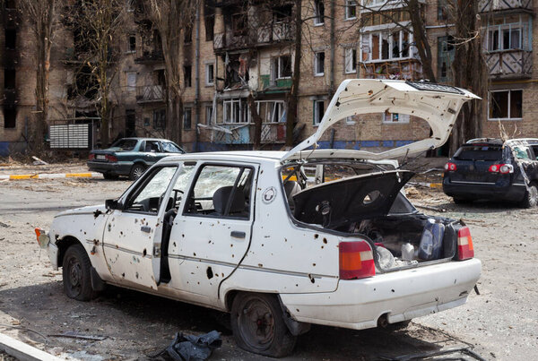 Ирпин, Киевская область, Украина - 12 апреля 2022 года: Российское вторжение на Украину. Автомобиль поврежден русскими обстрелами. Жилой район, разрушенный российскими бомбардировками. Следы обстрела и огня. 