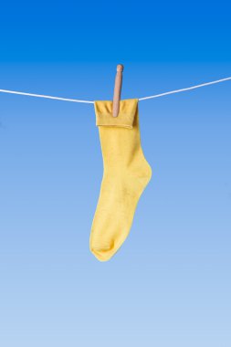yellow sock on washing line against blue background clipart