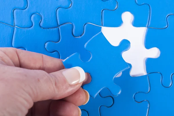 Woman's hand placing missing piece in Jigsaw puzzle  signifying — Stock Photo, Image