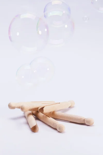 Wooden dolly pegs and bubbles on white background — Stock Photo, Image