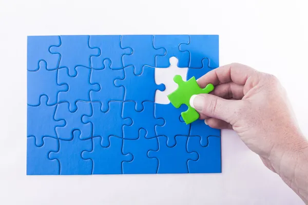 Woman's hand placing Jigsaw puzzle piece off different color sig — Stock Photo, Image