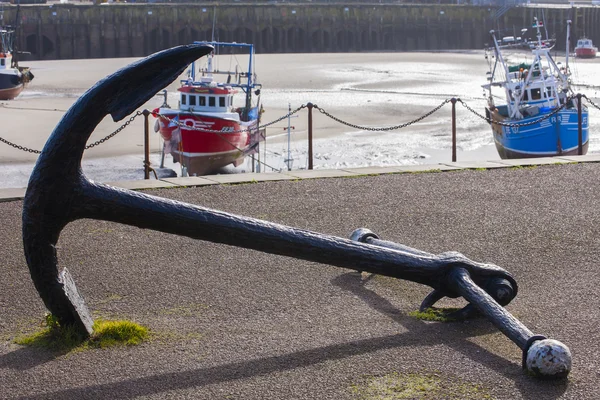 Heavy iron anchor and fishing boats at low tide — Stock Photo, Image