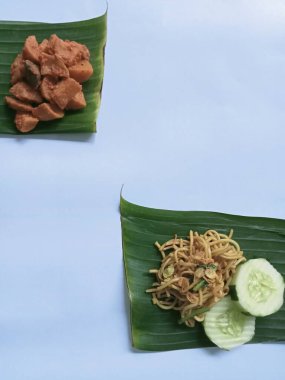 Cava eriştesi, patates sote ve muz yaprağı üzerinde servis edilen salatalık, izole edilmiş beyaz. Buharda erişte, baharatlı patates sote ve yeşil yapraklı salatalık..