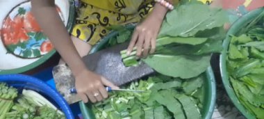 Küçük kız el, tahta kesme tahtasındaki bıçakla taze marul kesiyor.