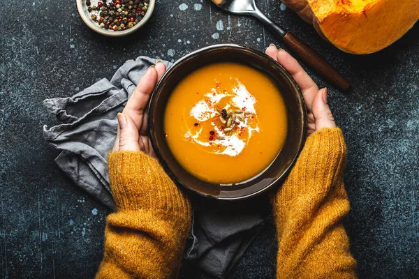 Weibliche Hände mit einer Schüssel Kürbissuppe — Stockfoto