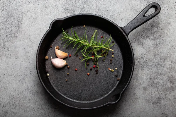 Black cast iron frying pan with rosemary, garlic, pepper top view — Stock Photo, Image