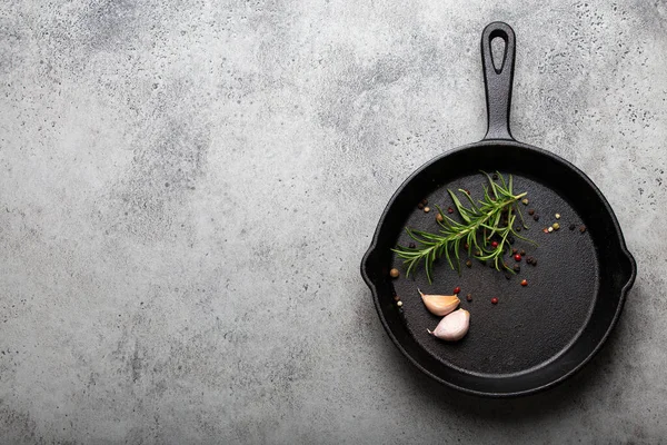 Cast iron frying pan with rosemary, garlic, pepper, oil copy space — Stock Photo, Image