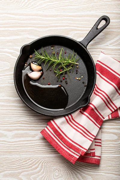 Padella nera in ghisa con rosmarino, aglio, pepe, olio — Foto Stock