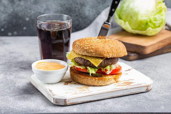Delicioso hambúrguer perfurado com faca com molho e cola — Fotografia de Stock