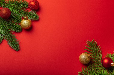 Kırmızı arka planda Noel süslemeleri ve köknar ağacı dalı