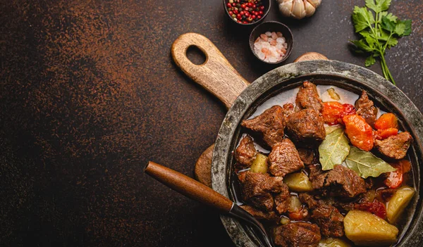 Ragoût de viande de bœuf aux légumes et sauce dans un pot en métal rustique vue du dessus espace de copie — Photo
