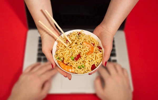 Female courier handing noodles bowl to man at computer, food delivery — Stock Photo, Image