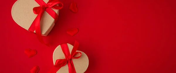 Две обернутые подарочные коробки в форме сердца на красном фоне, День Святого Валентина — стоковое фото