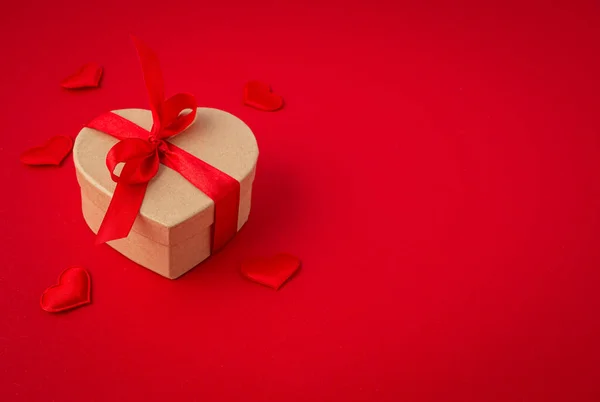 Подарочный коробок в форме сердца с луком на красном фоне, День Святого Валентина — стоковое фото