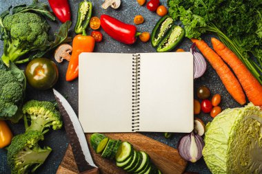 Empty paper notepad and assorted fresh vegetables on rustic concrete table