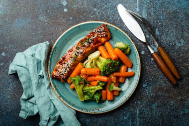 Grilled salmon fillet steak in teriyaki sauce with roasted vegetables carrot and broccoli