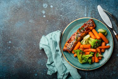 Grilled salmon fillet steak in teriyaki sauce with roasted vegetables carrot and broccoli