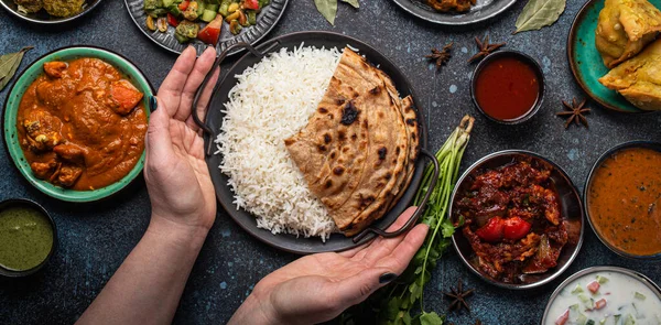 Жіночі руки, що служать індійському буфету етнічної їжі на бетонному столі. — стокове фото