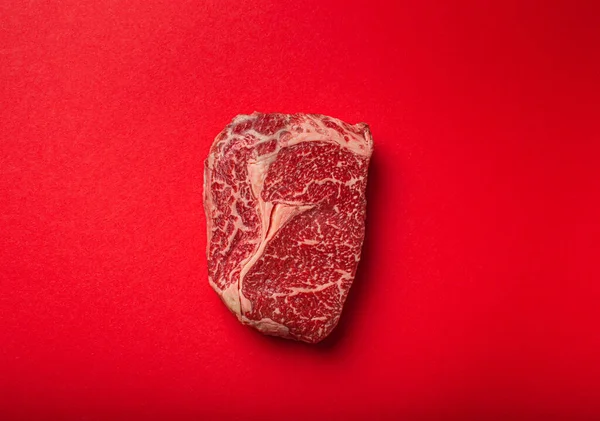 Råkött nötkött prime cut steak Ribeye på ren röd bakgrund uppifrån, nötkött koncept banner minimalism — Stockfoto