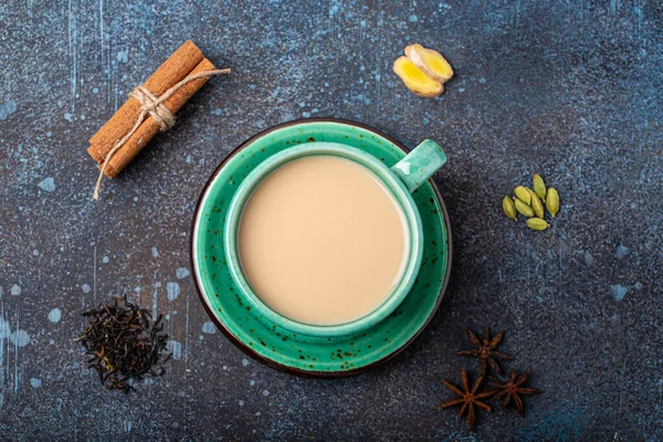 Индийский чай горячий напиток с молоком и специями в деревенской зеленой чашки с ингредиентами для приготовления чай масала — стоковое фото