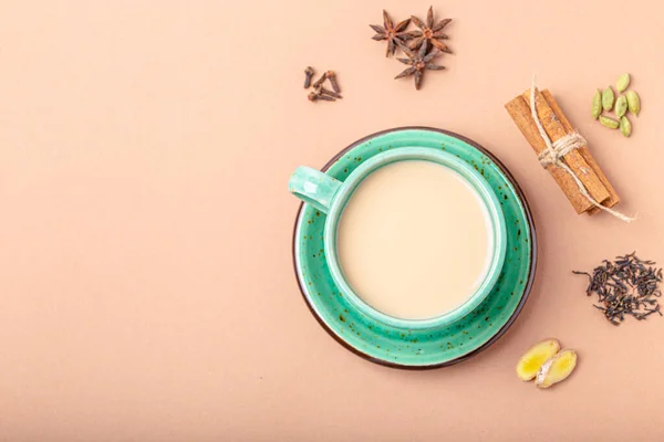 Индийский чай с молоком и специями в деревенской зеленой чашке с ингредиентами для приготовления чая масала — стоковое фото