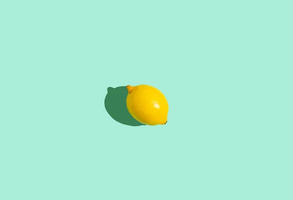 Amarelo inteiro um limão no centro do fundo azul mínimo na luz do sol brilhante com sombra dura — Fotografia de Stock