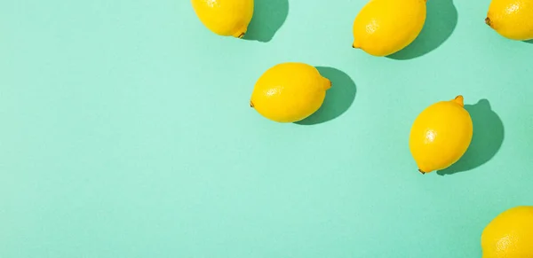 Żółte całe cytryny na minimalnym niebieskim tle na jasnym świetle słonecznym z twardym wzorem cieni — Zdjęcie stockowe