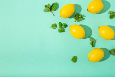 Minimum mavi arka planda naneli limonlar. Güneş, arka planda sert gölgeler bırakıyor.