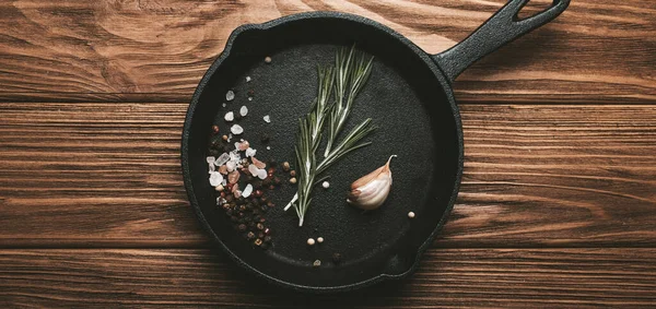 Padella nera in ghisa padella padella padella con ingredienti di cottura degli alimenti rosmarino fresco, aglio, sale e pepe — Foto Stock