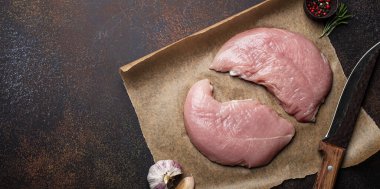 Türkiye biberiye, sarımsak ve baharatlı fırın kağıdı üzerine çiğ fileto koyuyor