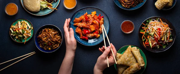 Chinesisches Gericht auf dem Tisch, weibliche Hände halten Essstäbchen — Stockfoto