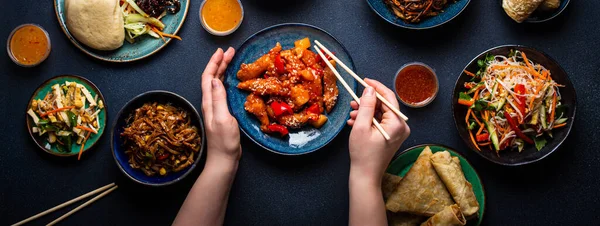 Китайські страви на столі, жіночі руки з паличками для їжі. — стокове фото