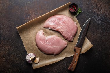 Türkiye biberiye, sarımsak ve baharatlı fırın kağıdı üzerine çiğ fileto koyuyor