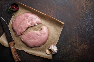 Türkiye biberiye, sarımsak ve baharatlı fırın kağıdı üzerine çiğ fileto koyuyor