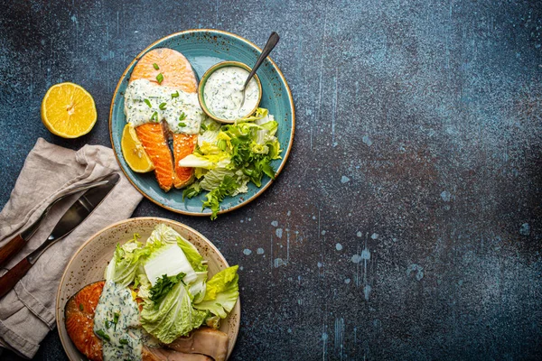Gesunde Mahlzeit gegrillte Lachssteaks mit Dillsoße und Salatblättern auf zwei Tellern — Stockfoto
