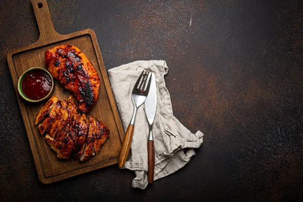 Gegrilltes Puten- oder Hühnerfilet mit roter Sauce serviert und in Scheiben geschnitten auf einem Holzschneidebrett — Stockfoto