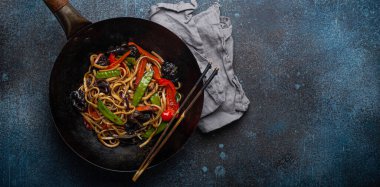 Siyah tava fotokopi alanında sebzeli erişte kızartır.