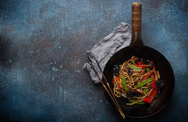 Siyah tava fotokopi alanında sebzeli erişte kızartır.