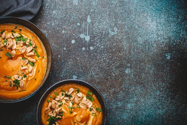 Eine Keramikschüssel Mit Kürbiscremesuppe Dekoriert Mit Erdnüssen Auf Dunklem Steinhintergrund — Stockfoto