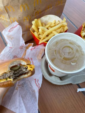 Arka planda bir peynirli burger, Barnaul 'daki bir McDonald' s fast food restoranından alınmış patates kızartmasıdır. Rusya, Barnaul, 29 Ağustos 2021