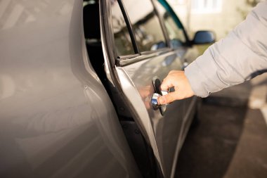 Adam gri bir arabanın arka kapısını açıyor. Adam arabanın kapısını açıyor. seçili odak