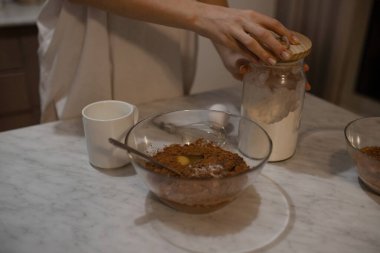The girl prepares a pie, a chocolate cake. A woman kneads the dough. Opens a jar of flour. Selectiv focus. Close-up.