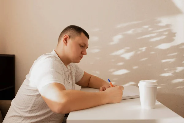 The man writes notes in the diary. A man writes notes at home. — Stock Photo, Image