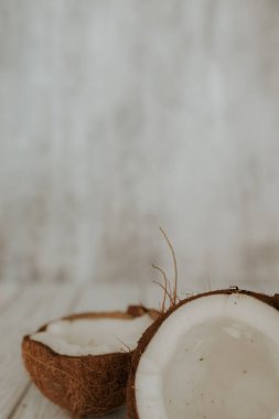 Bir hindistan cevizinin iki yarısı arka planda yatar. Tahta beyaz zeminde hindistan cevizi meyvesi. Seçici odaklanma. dikey resim