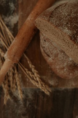 Tahta arka planda ev yapımı kabuklu ekmek pişirmek. Çavdar ekmeğinin yarısı. Buğday, ekmek, un, dikey fotoğraf