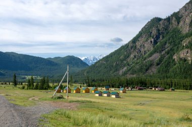 Dağların zirveleri gökyüzüne karşı beyaz bulutlarla. Yaz güneşli bir gün. Dağ asfalt yolu
